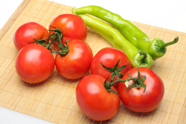 istock Tomatoes and green peppers on a white background 992825098