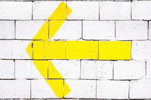 A yellow arrow on a brick wall as a background