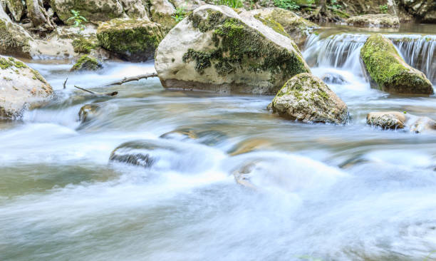 istock Beautiful scene of small waterfall with stone cascade and large rocks covered with moss 992828850