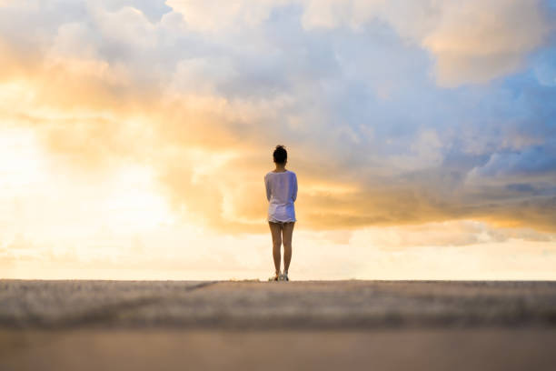 istock Woman looking at the sky during sunset. 992829064