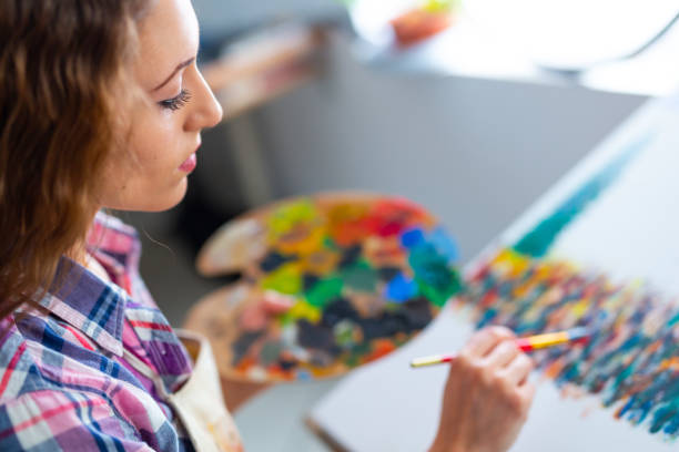 istock Young woman sitting and drawing 992836644