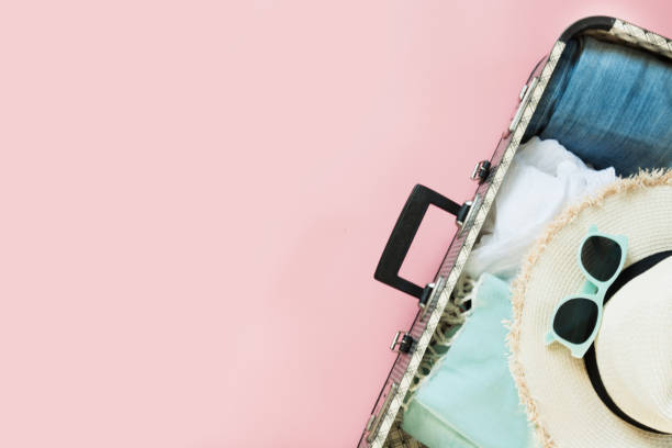 istock Open suitcase with female clothes for trip on pastel pink. Top view with copy space. Summer concept travel. 992837208