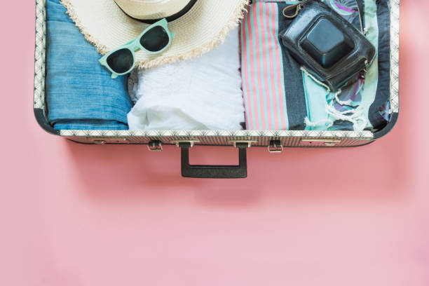 istock Open suitcase with female clothes for trip on pastel pink. Top view with copy space. Summer concept travel. 992837212