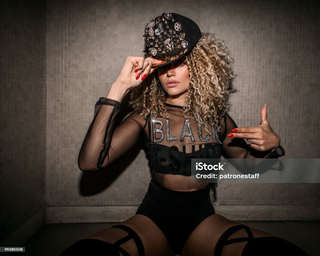 Beautiful and gangster woman sitting and making hand gesture Rapper Stock Photo