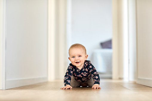 Sonriente niño gateando en pasillo en casa photo