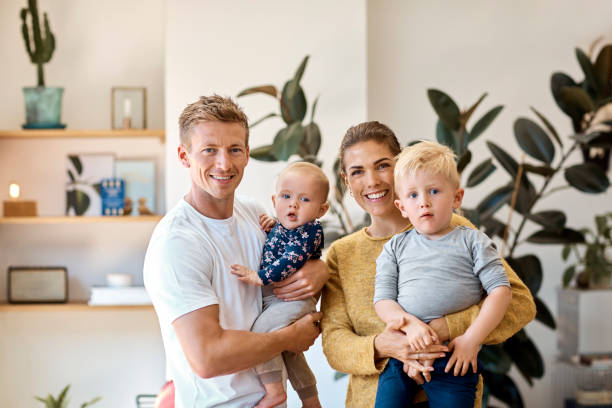 Happy parents carrying children at home Portrait of smiling parents carrying children at home. Loving family of four is spending leisure time together. They are wearing casuals. scandinavian culture stock pictures, royalty-free photos & images