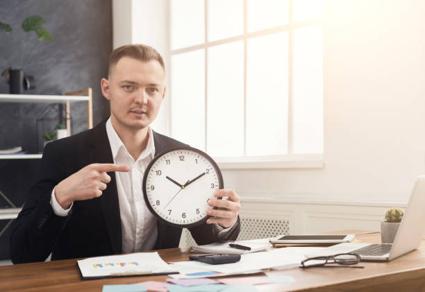 istock Businessman holding clock and pointing at it 992859450