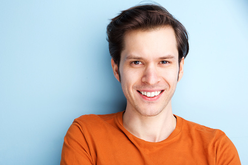 Close up portrait of happy man in orange shirt on blue background