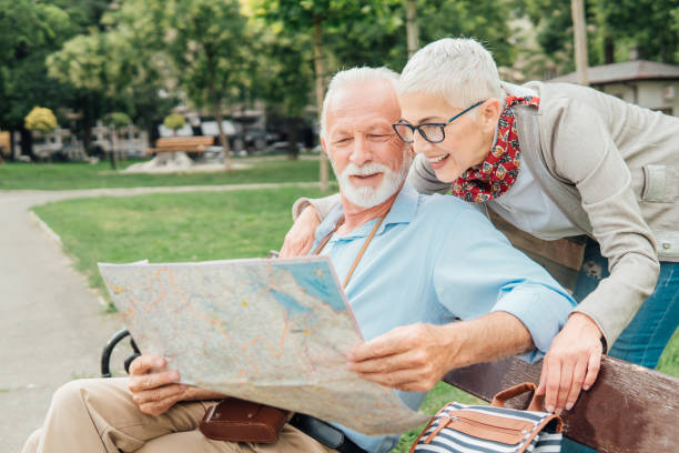 istock Man sitting on the bench while reading a map and woman hugging him from behind 992864014