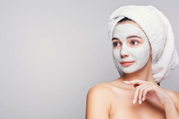 istock Beautiful girl with applied clay mask at white background 992867306