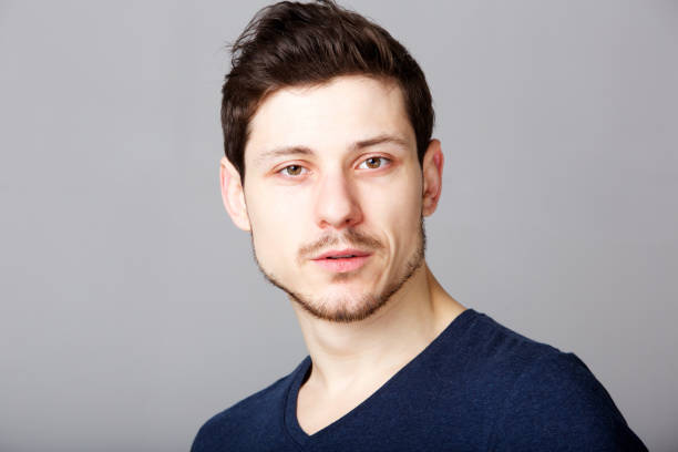 istock young man with serious expression against gray background 992875640