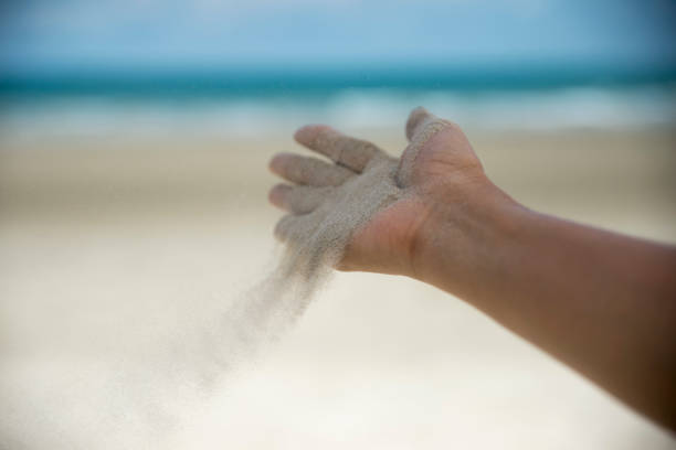 lascialo andare, mano della libertà e concetto di rilascio. lascia andare la donna che rilascia sabbia sulla bellissima spiaggia di mare e sullo sfondo dell'acqua blu. - releasing foto e immagini stock