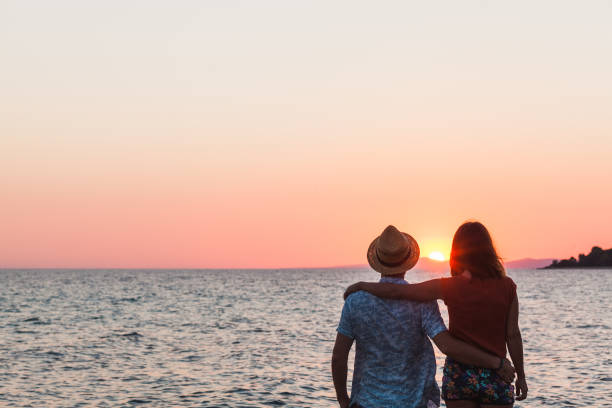 istock Young couple enjoying sunset by the sea 992879504