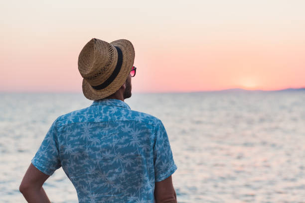 istock Young man enjoying sunset by the sea 992879956