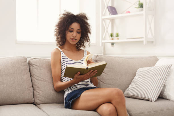 istock Cozy home. Young thoughtful woman with book 992880212