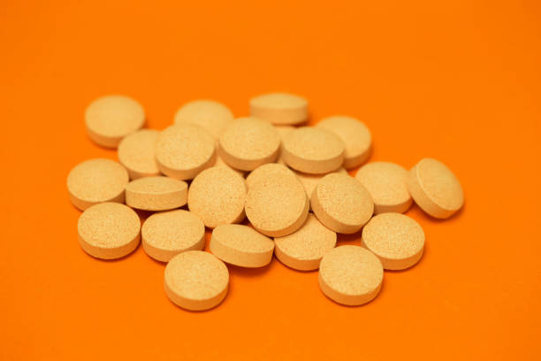 istock Piles of pills on orange background (medicine and health) 992888846