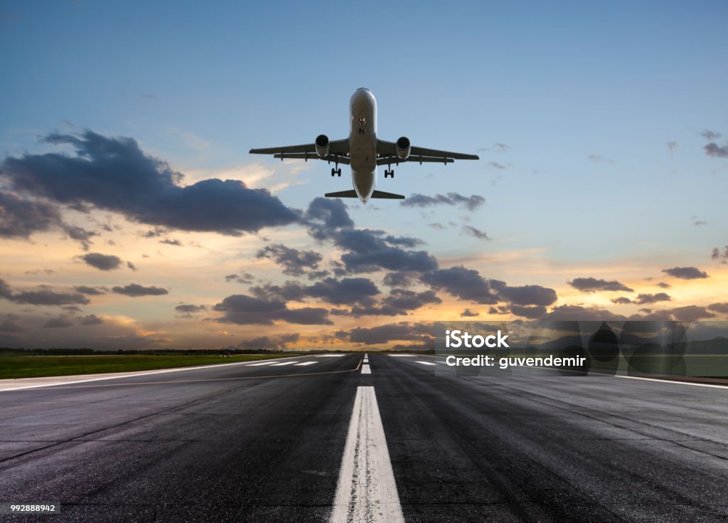 Samolot pasażerski startujący o zachodzie słońca - Zbiór zdjęć royalty-free (Pas startowy)