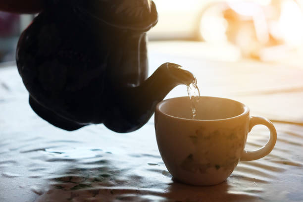 istock Teapot pouring hot tea in cu 992889418