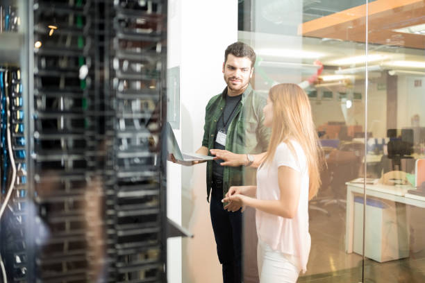 colleagues discussing in office server room - support network imagens e fotografias de stock