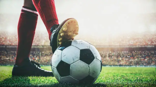 Photo of feet of soccer player tread on soccer ball for kick-off in the stadium