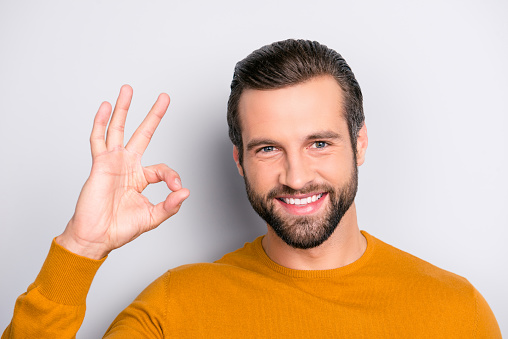Close up portrait of professional successful expert excited satisfied handsome delightful cheerful glad with beaming smile freelancer demonstrating ok symbol isolated on gray background