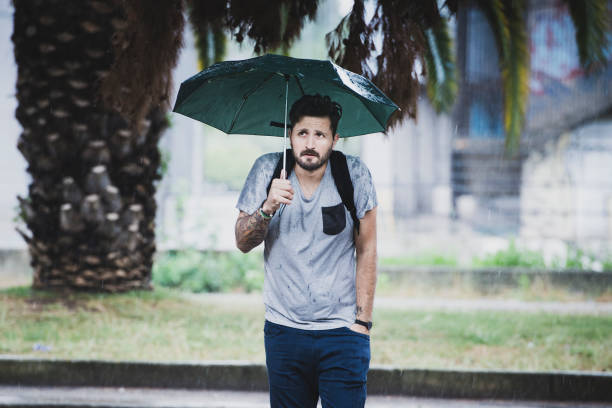 giovane adulto che aspetta sotto la pioggia - under the weather foto e immagini stock