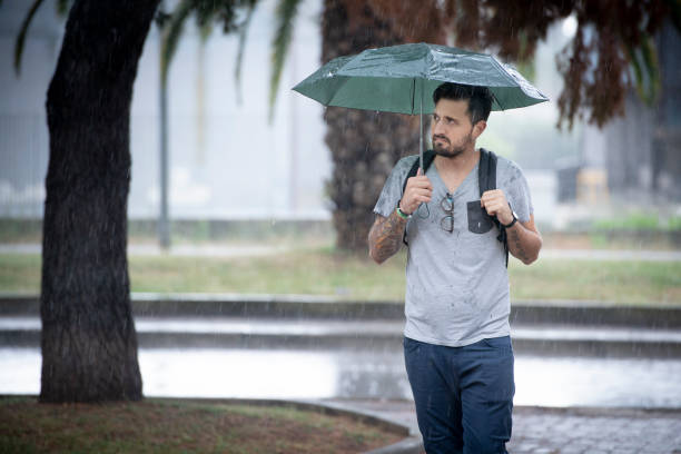 istock Young Adult Man Walking Under The Rain 992901982