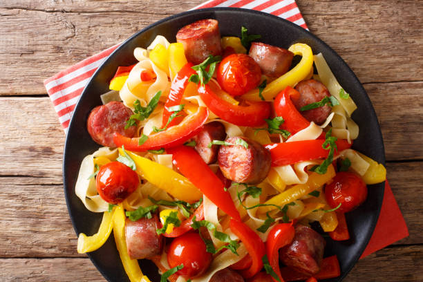 istock Pasta with stewed bell pepper and sausages close-up on a plate. Horizontal top view 992910646