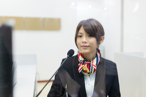A smiling Chinese bank teller standing behind the counter.