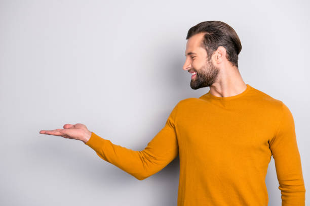 istock Profile side half-faced view photo of cheerful excited joyful handsome entrepreneur presenting new successful project start up position on hand copy-space empty blank place isolated on gray background 992924062
