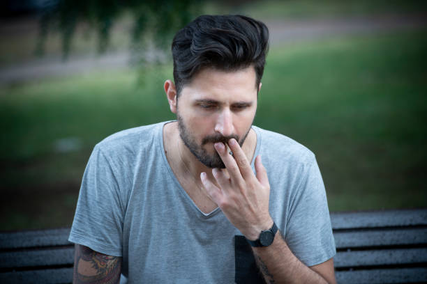istock depressed Michele sitting on a bench smoking a cigarette 992928236