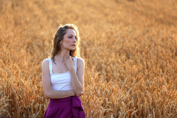 istock Young beautiful girl standing on wheat field alone 992928296