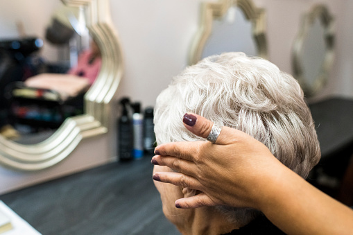 Senior woman looking into mirror, confident with her new hairstyle