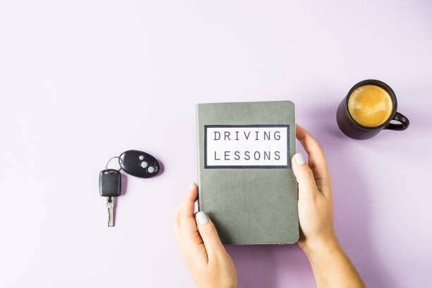 female hands hold a training book for driving lessons and studying traffic rules. getting a driving license concept. on a violet background - driving training car safety imagens e fotografias de stock