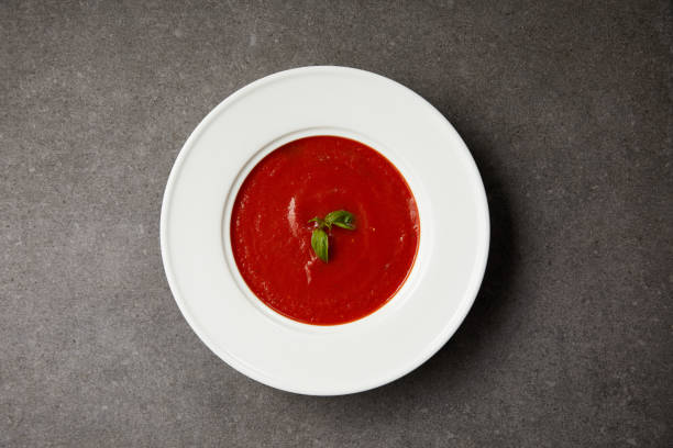 istock top view of red tomato soup with basil in white plate on grey table 992980704