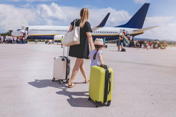 istock Mother and daughter with their luggage boarding a plane 992986368