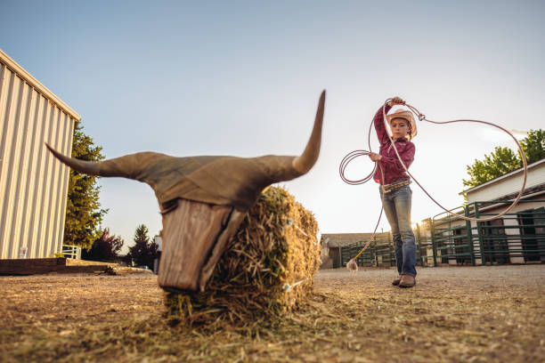 Portrait of young cowgirl practicing roping with lasso at the ranch.  Outside Salt Lake City, Utah.