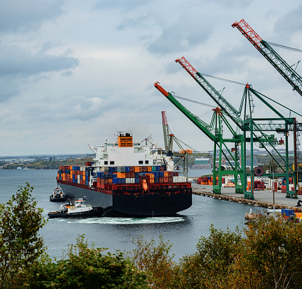 Tugboats assist with the docking of a container ship in Halifax harbor.