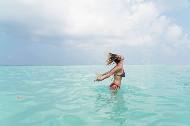 beautiful young women enjoying in the sea - splashing maldives human hair spray imagens e fotografias de stock
