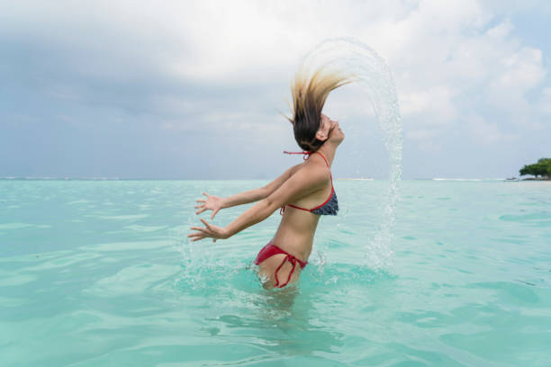 beautiful young women enjoying in the sea - splashing maldives human hair spray imagens e fotografias de stock