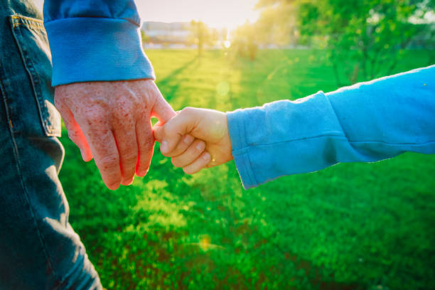 father and son holding hands at sunset, parenting concept