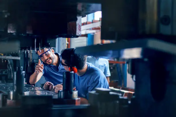 Workers working on the machine for cutting metal sheets