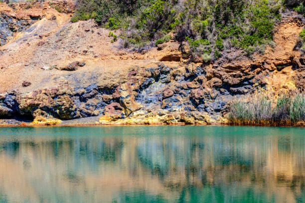 lago muito colorido e rochas nas proximidades de uma mina na ilha de elba na toscana, itália. mineração de minério de ferro de superfície mineral minério de ferro concomitante, industrial - tuscany abandoned - fotografias e filmes do acervo