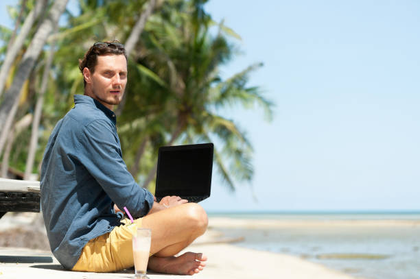 istock Man freelancer working in laptop sitting at the beach 993090836