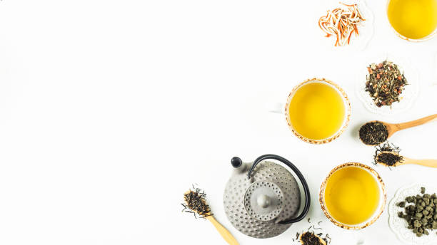 istock Gray iron kettle among different kinds of dry tea and cups with a ready drink on a white table. Top view, flat lay. Copy space 993097656
