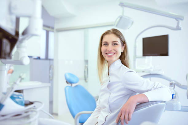 Cute Dentist Technician Smiling While Sitting In Dental Clinic Cute Dentist Technician Smiling While Sitting In Dental Clinic dental hygienist stock pictures, royalty-free photos & images