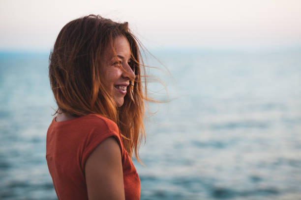 istock Young woman enjoying sunset by the sea 993105820