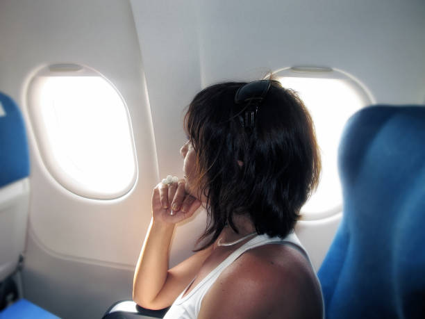 istock Young woman looking from airplane window from her seat 993106402