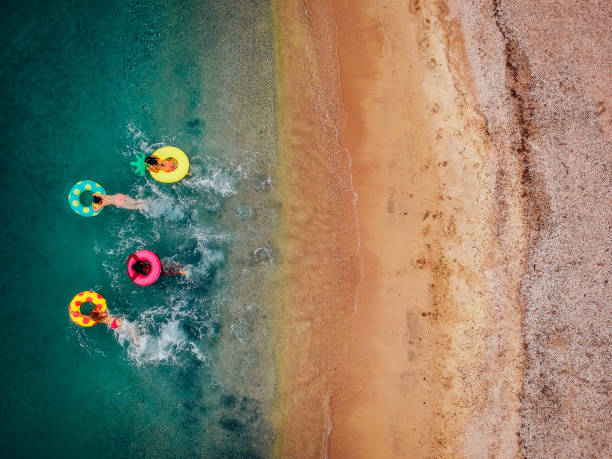 girlfriends having fun on floaties in water - bikini summer vacations looking down imagens e fotografias de stock