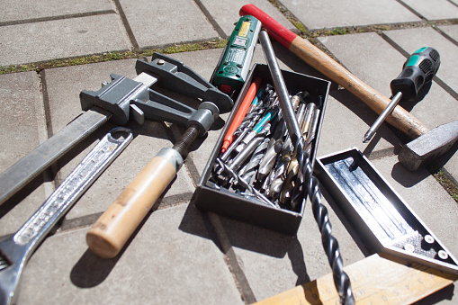 Repair tools. File, hummer, corner ruler, drill bits, screwdriver on stone background